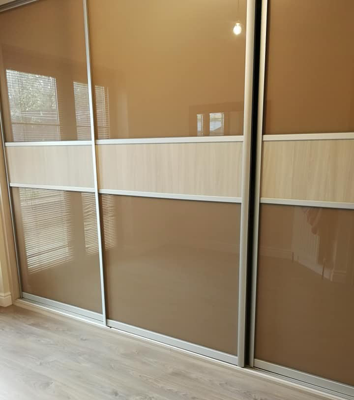 Sliderobe with high gloss doors and a section of wooden panelling