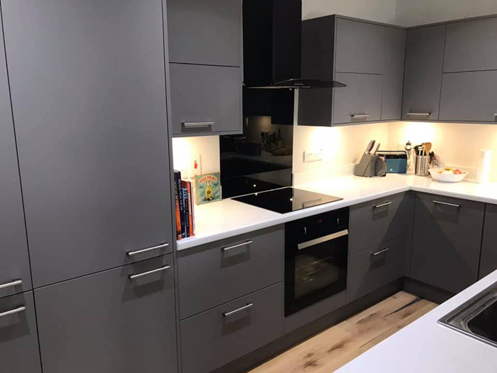 dark grey kitchen with white countertops and black cooker